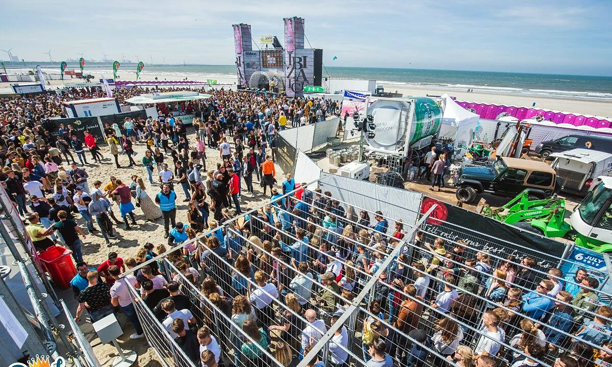 Bouwhekken die een strandfestival afbakenen, met publiek erachter